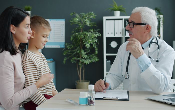 Doctor atendiendo a una mamá y su hijo en una clínica