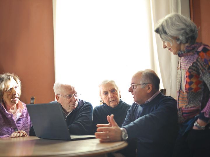 Group of older adults talking around a laptop