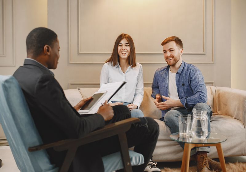 Smiling couple talking with their advisor at home