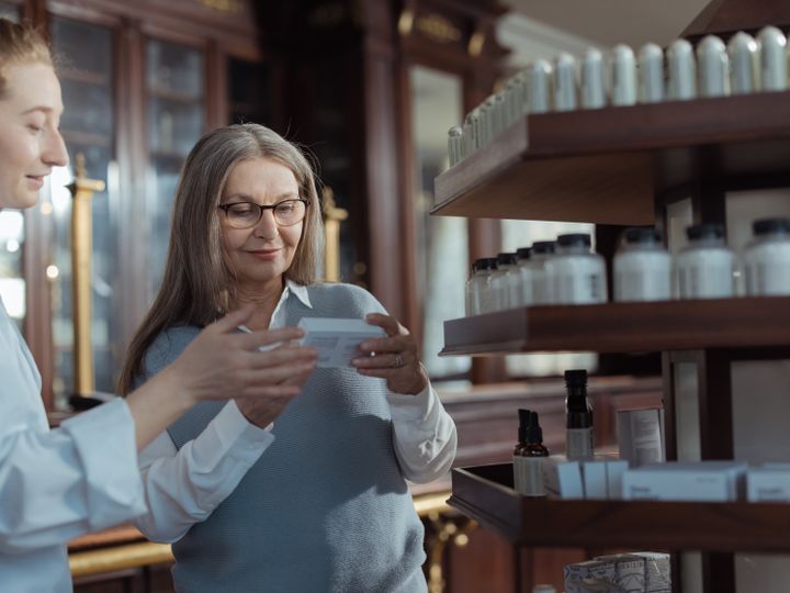 Agent helping an older woman at a pharmacy