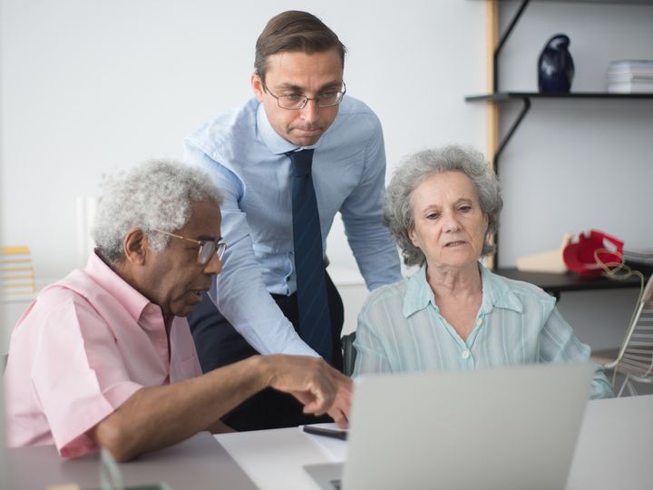 Agent reviewing options on a laptop with an older couple